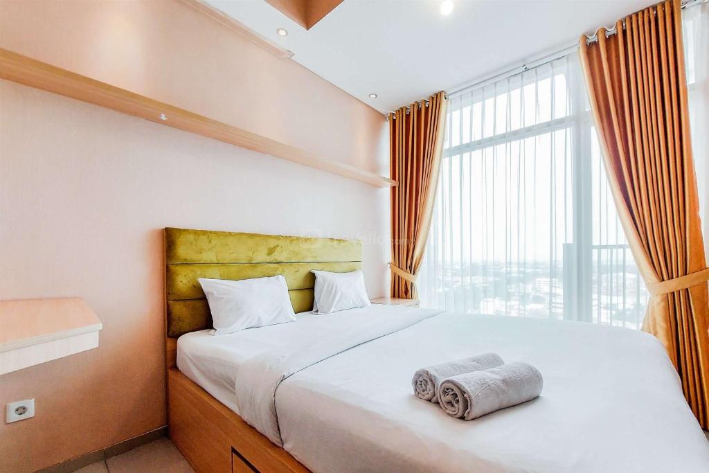 a bedroom with a bed with a large window at Homey and Modern Studio at Tree Park City Cikokol Apartment By Travelio in Tangerang
