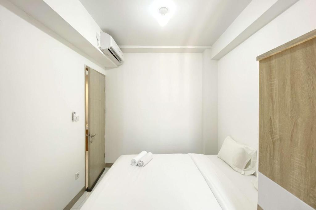 a white room with a bed and a door at Comfortable 2BR at Tokyo Riverside PIK 2 Apartment By Travelio in Rawalembang