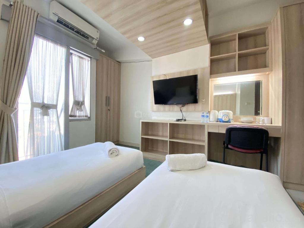 ein Hotelzimmer mit zwei Betten und einem Fernseher in der Unterkunft Beauty Studio No Kitchen at Easton Park Residence Jatinangor Apartment By Travelio in Sumedang