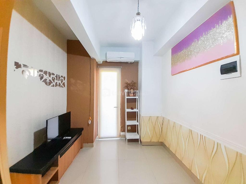 ein Wohnzimmer mit einem TV und einer Wand in der Unterkunft Homey and Warm 1BR at Student Castle Yogyakarta Apartment By Travelio in Seturan