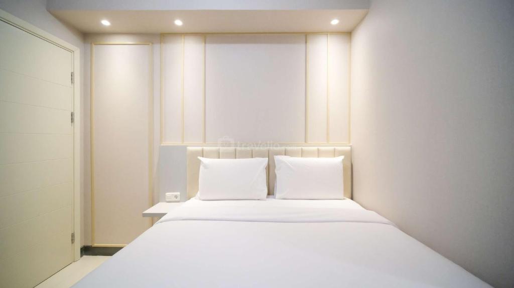 a bedroom with a white bed with two pillows at Luxury and Clean 2BR at Benson Supermall Mansion Apartment By Travelio in Surabaya