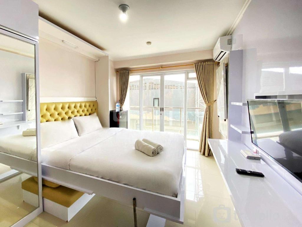 a bedroom with a large bed and a large window at Good Choice Studio Room at Gateway Pasteur Apartment By Travelio in Bandung