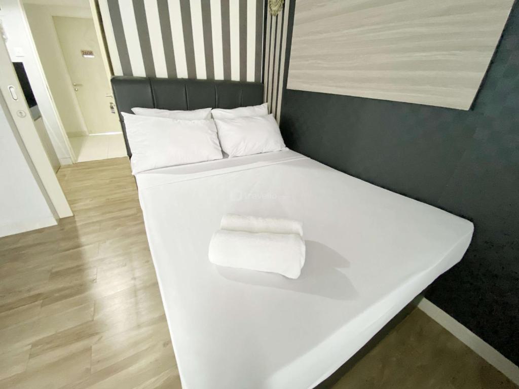 スマランにあるHomey and Cozy Living Studio Amartha View Apartment By Travelioの白いベッド(タオル2枚付)