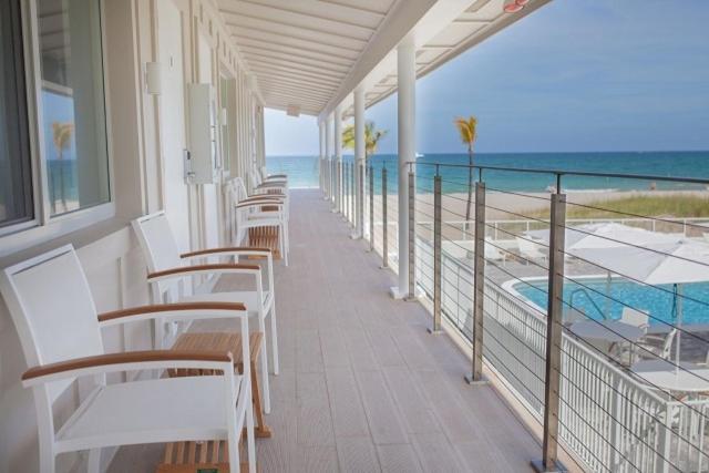 a balcony with white chairs and a swimming pool at Tides Inn Hotel in Fort Lauderdale