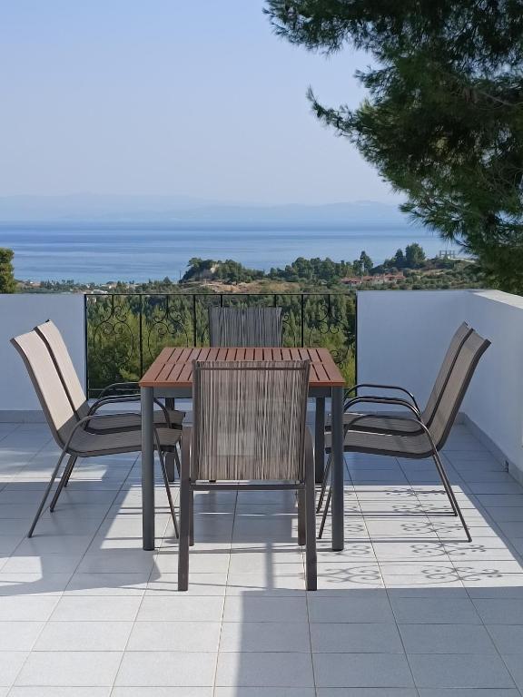 a wooden table and chairs on a patio with the ocean at Holiday home with view in Pefkochori