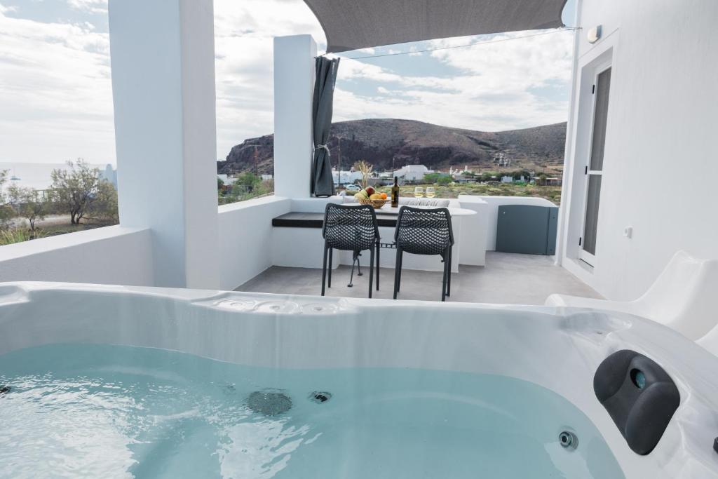 a white bathroom with a tub and a table and chairs at Red Beach Harmony suites Modestos in Akrotiri