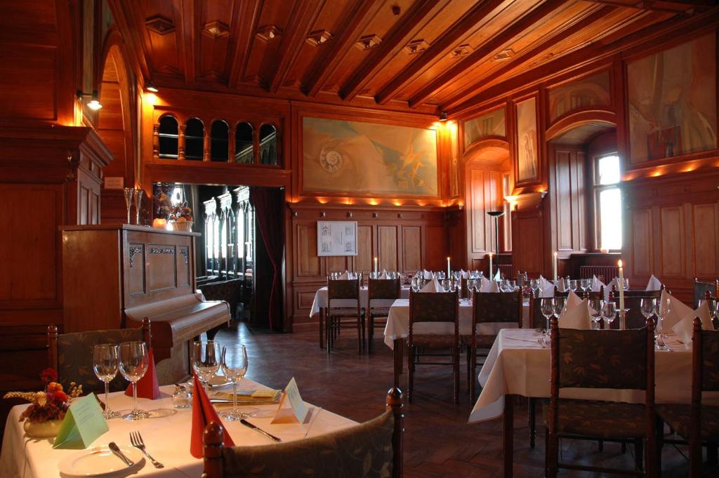 a dining room with tables and chairs and a piano at Schloss Herberge Hohenerxleben in Hohenerxleben