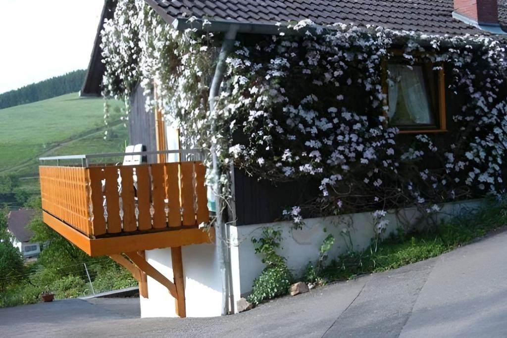 a bench sitting in front of a house with flowers at Small holiday cottage Ivy in Schuttertal