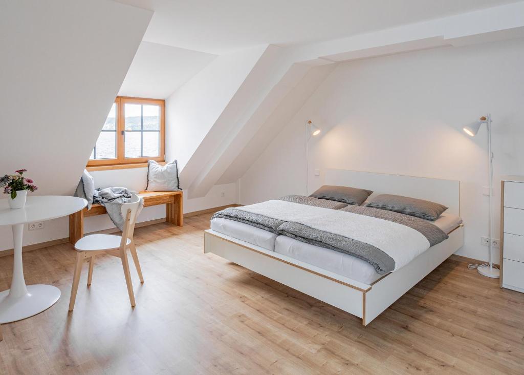 a white bedroom with a bed and a table at Ferienwohnungen SEEELF - Luv Stay in Überlingen