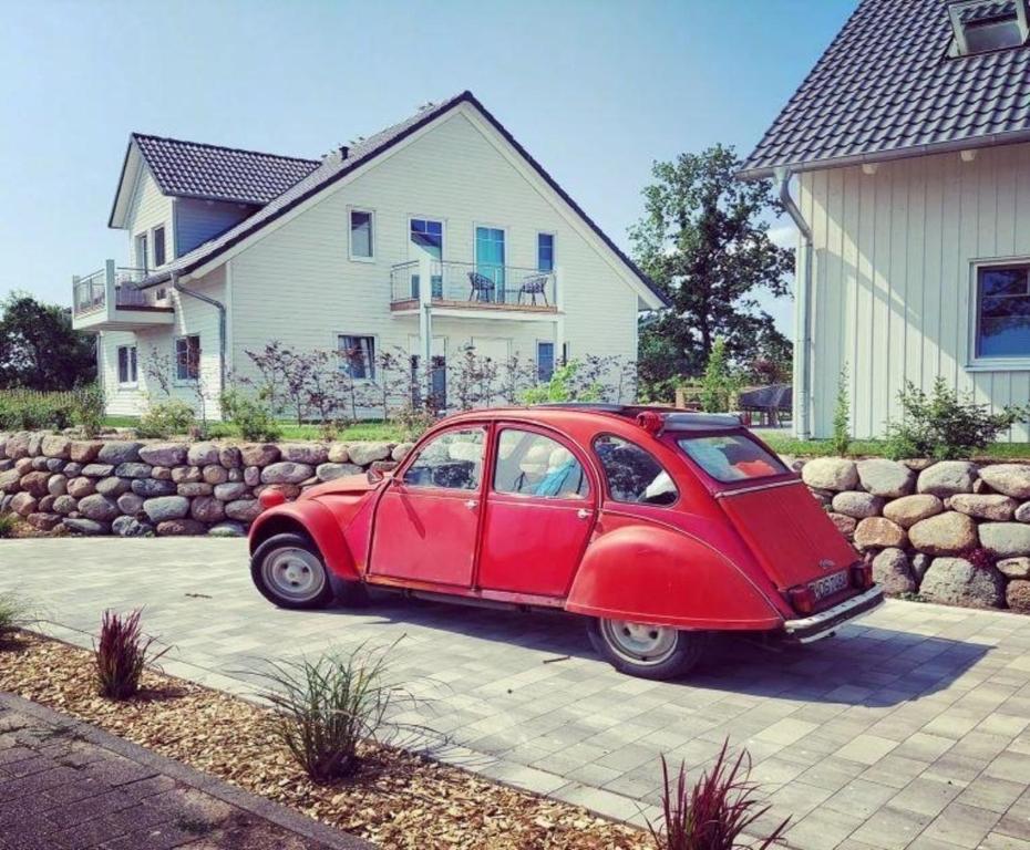a red car parked in front of a house at Barrierefreies Ferienhaus in Altwarp mit Sauna, Kamin und Wasserblick in Altwarp