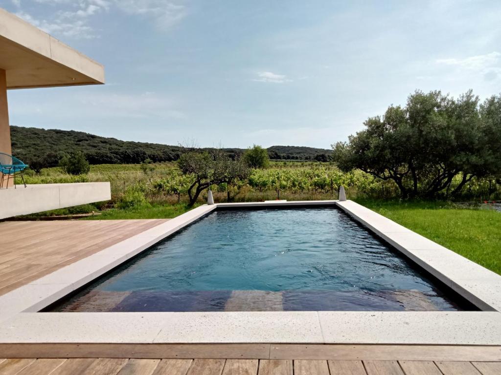 een zwembad in een achtertuin met een houten terras bij La villa des vignes in Castillon-du-Gard