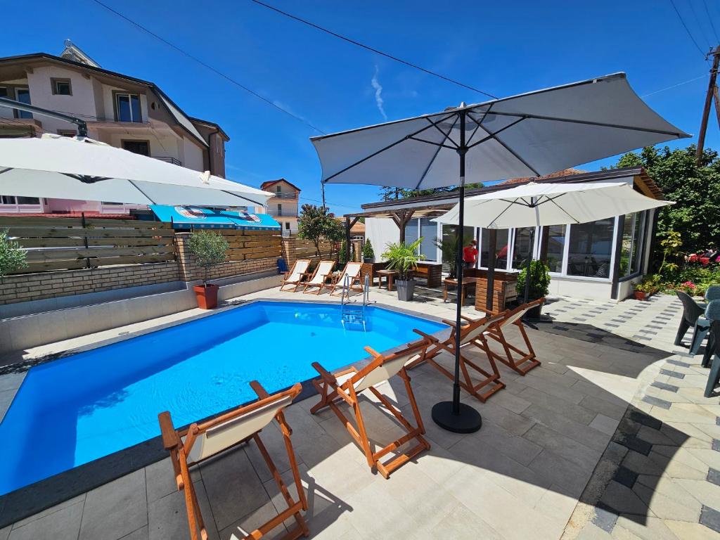 a swimming pool with chairs and an umbrella at Villa Pegasus Pestani in Ohrid