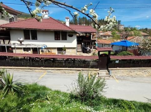 a fence in front of a house with a building at Dyadovata Kashta in Elena