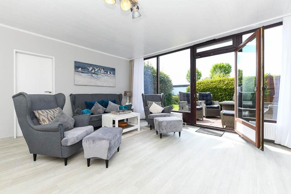 a living room with a couch and chairs and windows at Ferienhaus Meereskrone in Bensersiel
