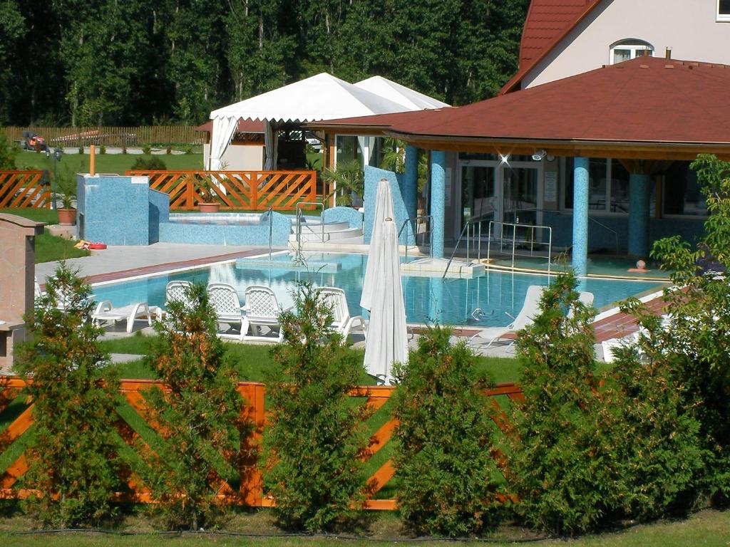 - une piscine avec un parasol blanc à côté d'une maison dans l'établissement Thermal Park Hotel Egerszalók, à Egerszalók