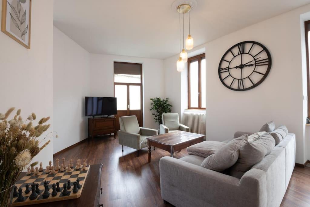 a living room with a couch and a clock on the wall at Cabana & L'Auberge Beaujolaise - Maison de Ville in Ouroux
