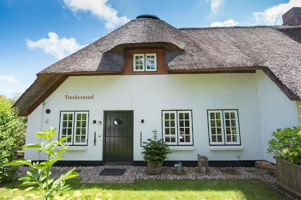 a white house with a thatched roof at Luxuriöses Apartment in Reetdachhaus in Tinnum