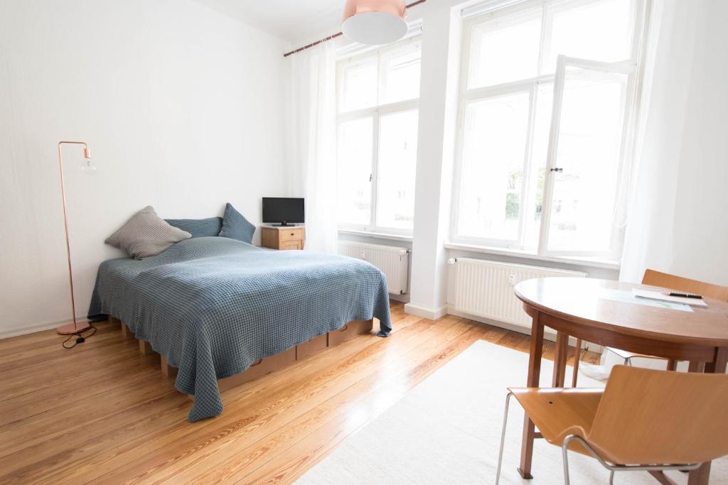 a bedroom with a bed and a table and windows at Studio Altbau in Weimar