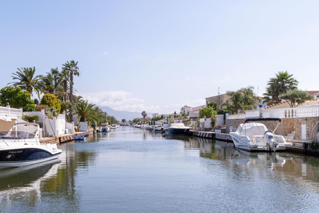 a river with boats docked next to buildings and palm trees at Jouvacations Villa 2 Freser con piscina compartida in Empuriabrava