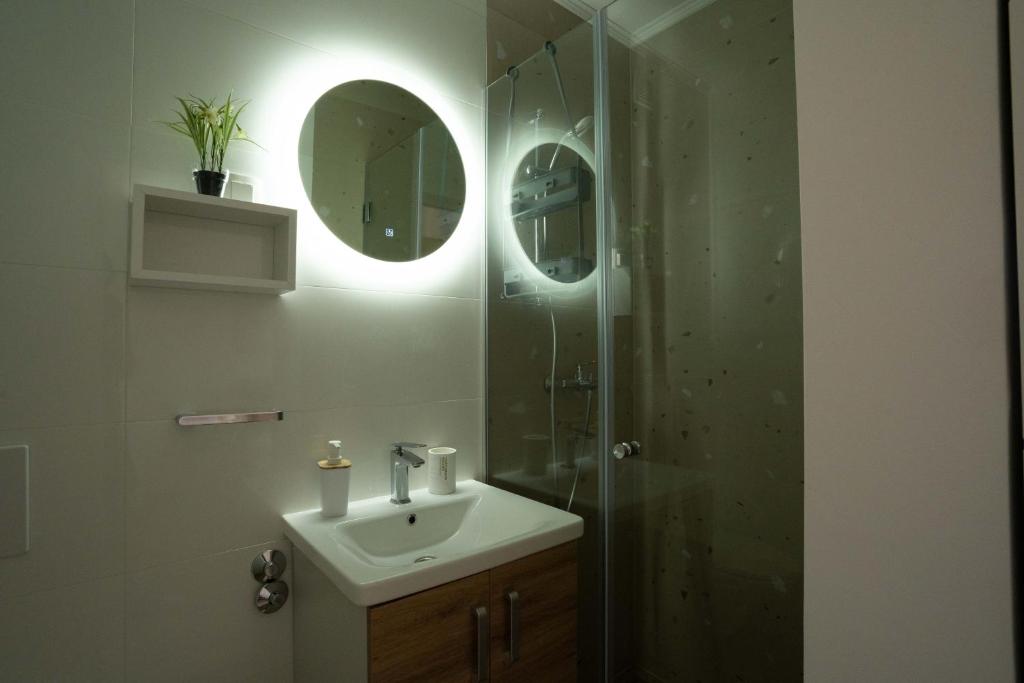 Un baño con lavabo y ducha con espejo. en Apartments & Rooms Petra, en Zadar