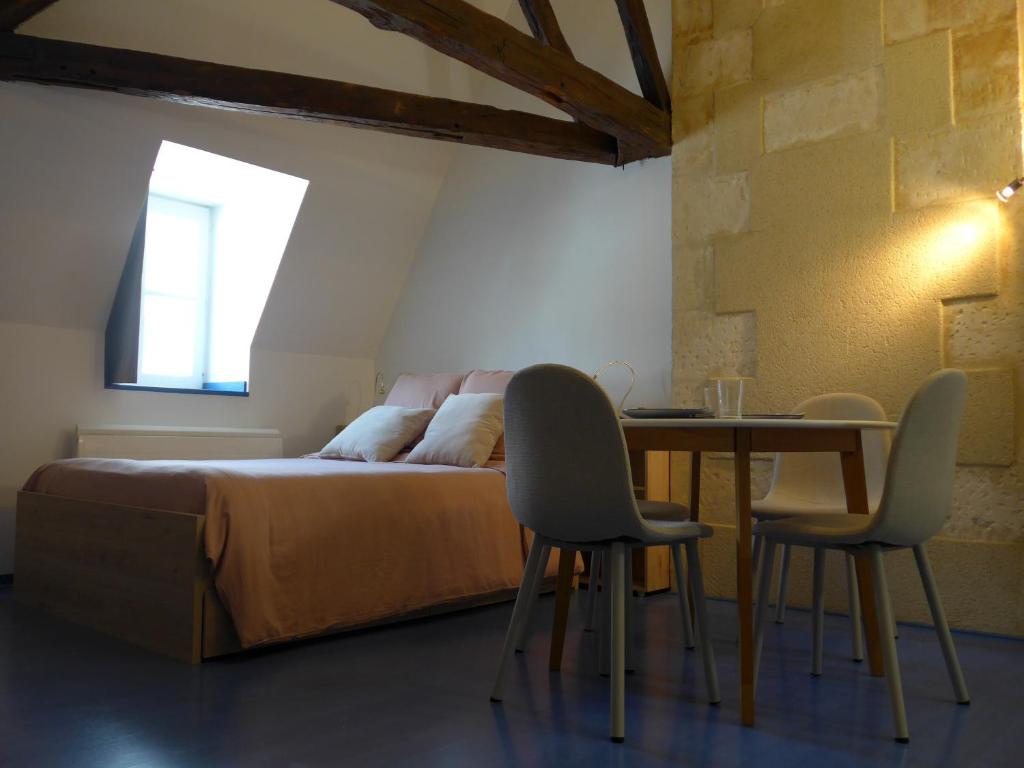 une chambre avec un lit, une table et des chaises dans l'établissement Charmant studio centre-ville, à Bourges