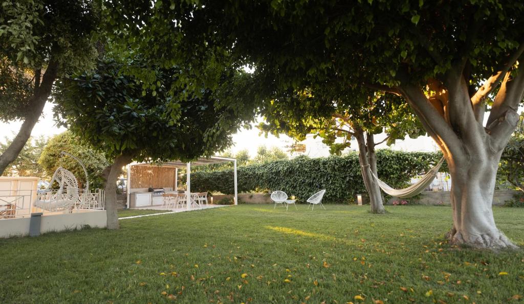 a park with two chairs and a hammock under two trees at June Home in Platanes