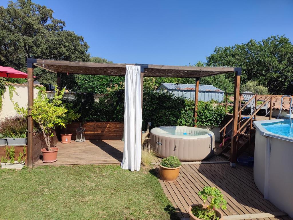 une cour avec un bain à remous et un kiosque dans l'établissement Maison au calme, à Saint-Quentin-la-Poterie