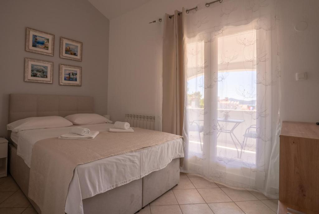a white bedroom with a bed and a window at Apartments & Rooms Petra in Zadar