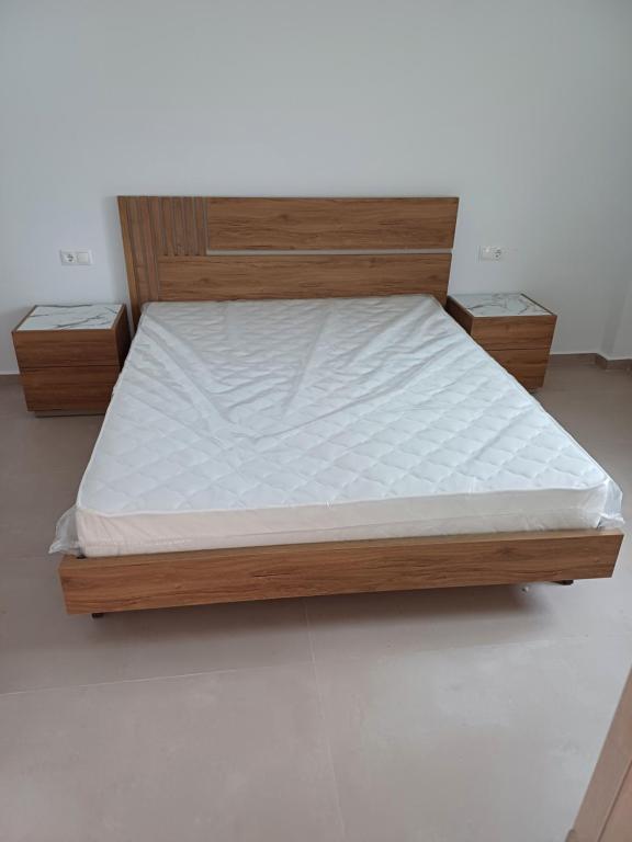 a bed with a wooden frame and white mattress at Mary Apartments in Stalida