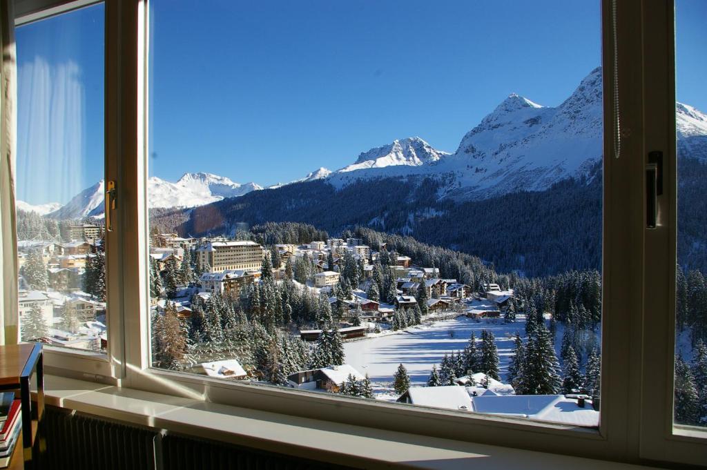 a view of a snowy mountain from a window at Viktoria B32 by Arosa Holiday in Arosa