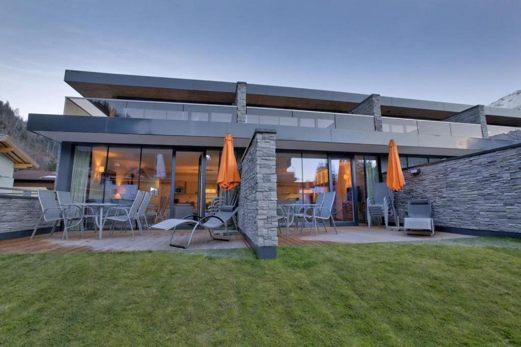 une maison avec une terrasse dotée de chaises et de parasols dans l'établissement Residenz Wildkogelbahnen Top 2, à Neukirchen am Großvenediger