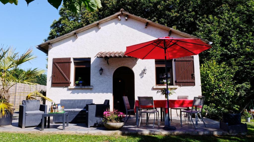 een huis met een tafel en stoelen en een rode paraplu bij Gite Saint Pardoux L'ortigier in Saint-Pardoux-lʼOrtigier