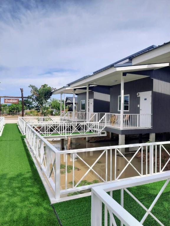 a house with white railings and a green lawn at Jira Hotel in Lampang