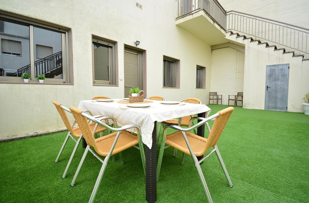 einen Tisch mit Stühlen und eine weiße Tischdecke auf einem Rasen in der Unterkunft Apartamento con terraza en San Vicente in O Grove