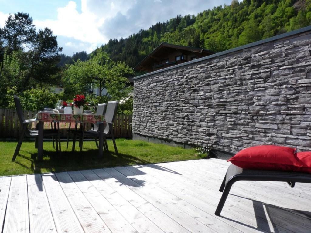 a table and chairs on a patio with a stone wall at Residenz Wildkogelbahnen Top 7 in Neukirchen am Großvenediger