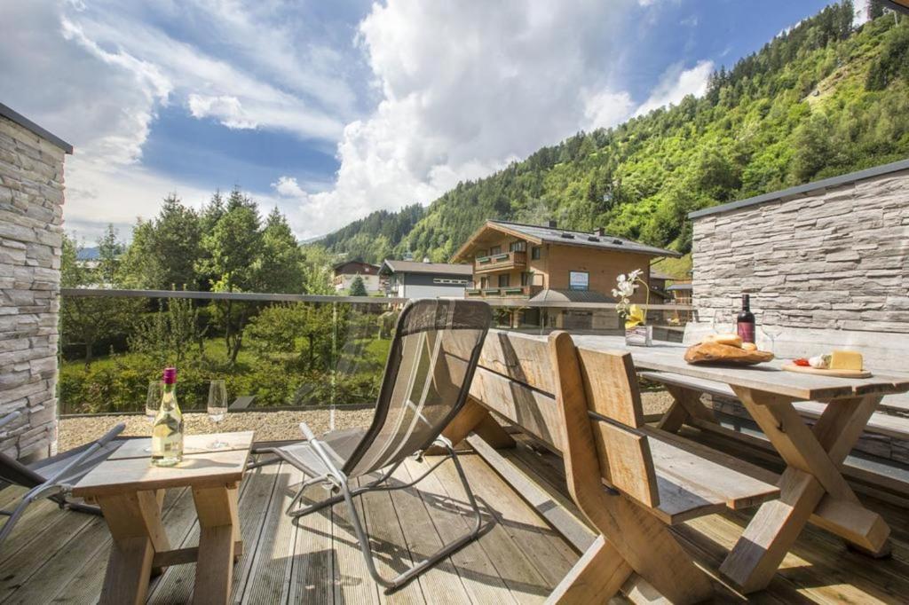 a wooden deck with a table and chairs on a balcony at Residenz Wildkogelbahnen Top 15 in Neukirchen am Großvenediger