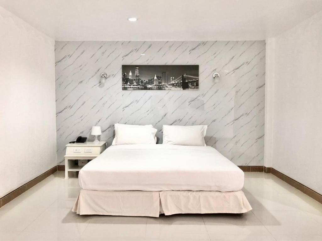 a bedroom with a large white bed and a wall at Dad D Resort by Lopburi Inn Resort in Lop Buri