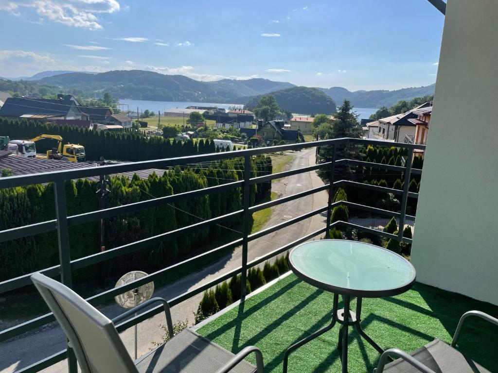 a balcony with a table and chairs and a view at Pokoje Gościnne nad Rożnowskim in Gródek Nad Dunajcem