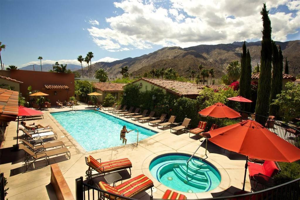 uma piscina com cadeiras e guarda-sóis num resort em Los Arboles Hotel em Palm Springs