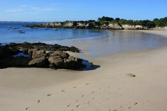 - une plage avec des rochers et l'océan avec des bateaux dans l'établissement Lomener-Maison plage à pied-Surfs et Paddles, à Ploemeur