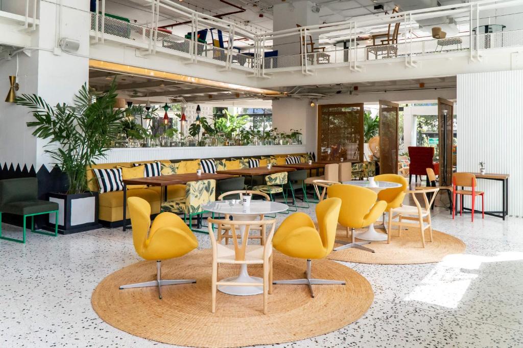 a restaurant with yellow chairs and tables in a room at Siam@Siam, Design Hotel Bangkok in Bangkok