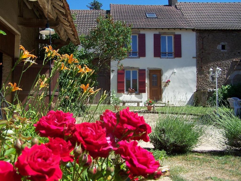 une maison avec des roses rouges devant une cour dans l'établissement Gite Vini Cella, à Nanton