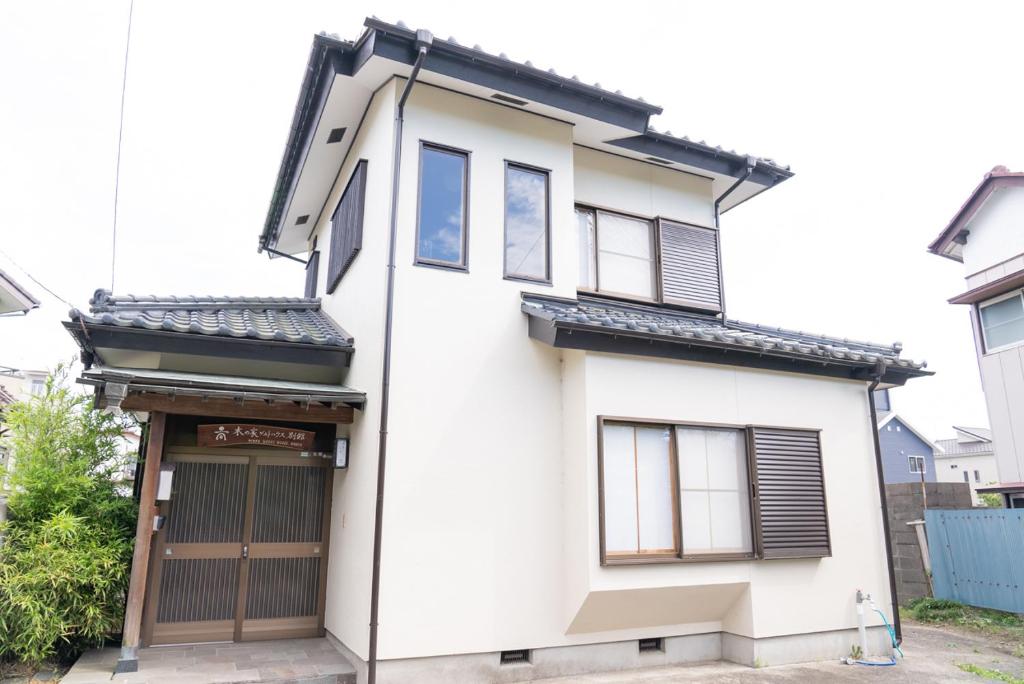 a white house with a black roof at 木の家ゲストハウス別館 in Mito