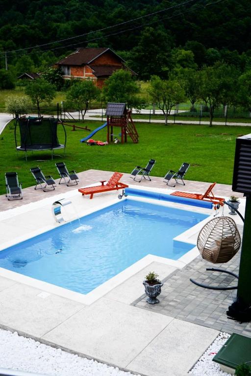 a large swimming pool with chairs and a playground at Villa Tasnim in Dobrenica