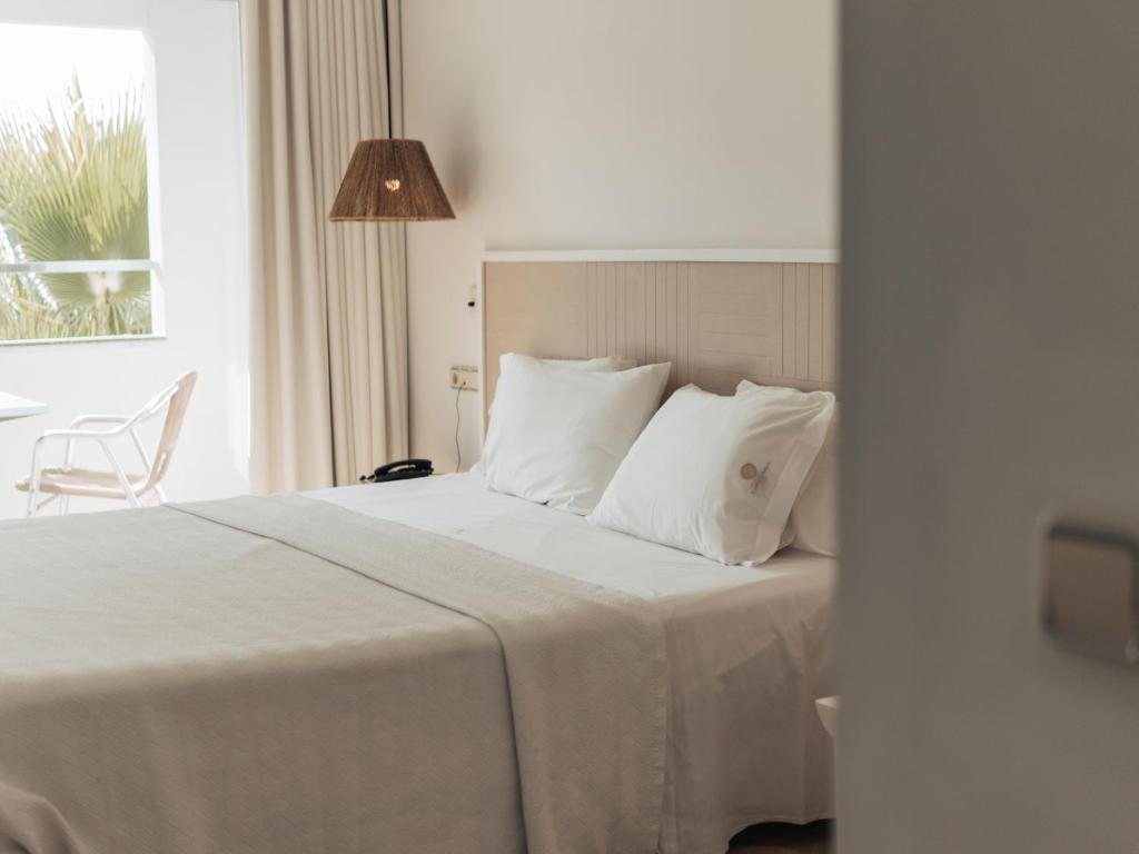 a bed with white sheets and pillows in a bedroom at Hotel MC San José in San José