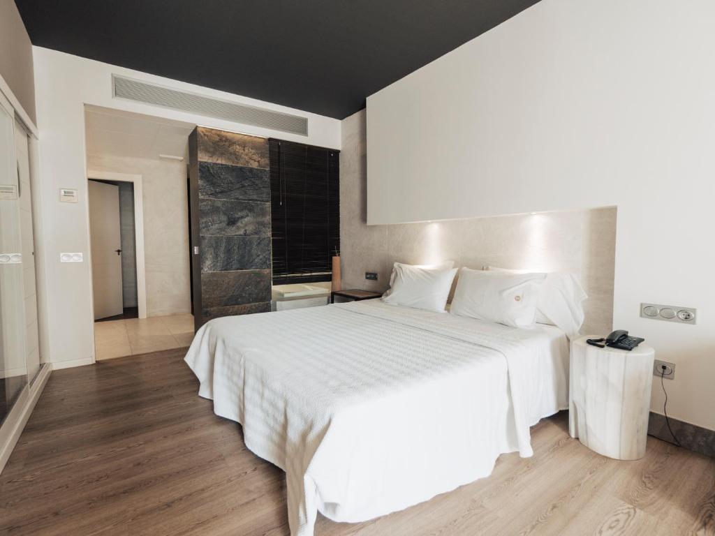 a bedroom with a large white bed with white sheets at Hotel MC San José in San José