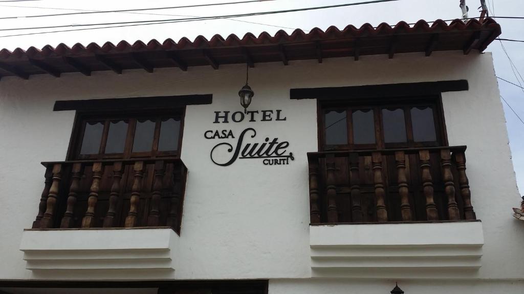 a sign on the side of a building with windows at Hotel Casa Suite Curiti in Curití