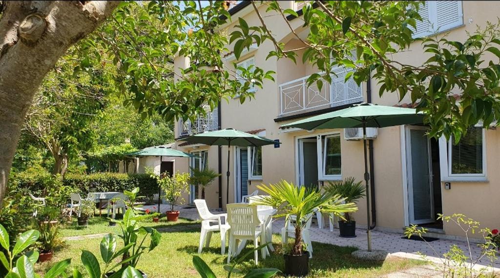 een patio met tafels en parasols voor een gebouw bij Garden Rooms Chiara in Poreč