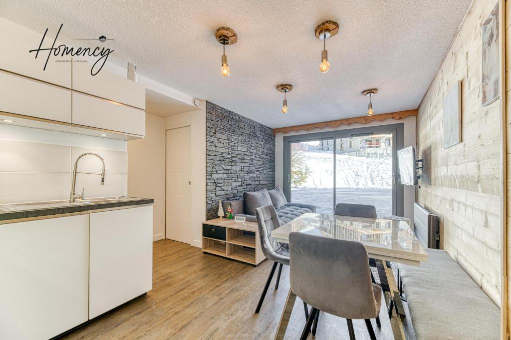 une cuisine et une salle à manger avec une table et des chaises dans l'établissement Homency - Résidence Les Mélèzes 14, à L'Alpe-d'Huez