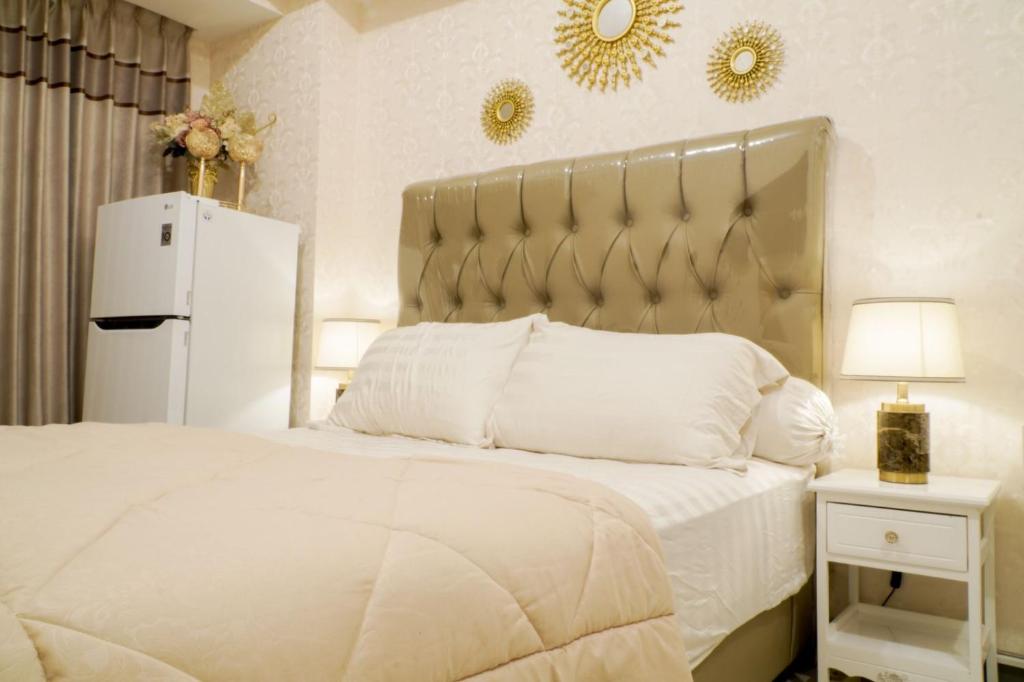 ein Schlafzimmer mit einem weißen Bett und einem Kühlschrank in der Unterkunft Let You inn in Surabaya